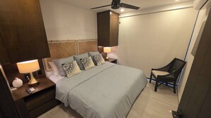 Ein Schlafzimmer mit Bett, Nachttischen, einem Sessel und einem Deckenventilator.