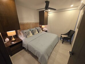 A bedroom with a bed, bedside tables, a chair, and a ceiling fan. - Condo 2 recámaras a pasos de playa Santa Cruz (Bahía de Santa Cruz Huatulco)