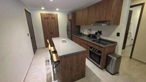 Eine moderne Küche mit Holzschränken, einer zentralen Kochinsel und einem eingebauten Backofen.