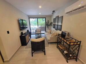 A modern living room with a sofa, a coffee table, a TV, and a coffee machine. - Condo 2 recámaras a pasos de playa Santa Cruz (Bahía de Santa Cruz Huatulco)