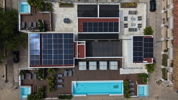 Ein Poolbereich auf dem Dach mit Solarmodulen, Liegestühlen und einem Schwimmbecken.