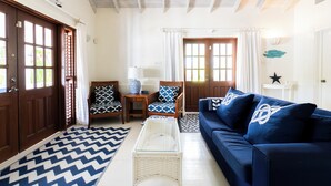 A living room with a blue sofa, patterned chairs, a glass coffee table, and a chevron-patterned rug.
