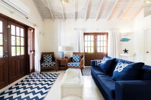 A living room with a blue sofa, patterned chairs, a glass coffee table, and a chevron-patterned rug.