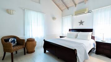 A bedroom with a large bed, a wicker chair, a small side table, and a star decoration on the wall.