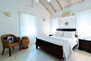 Ein Schlafzimmer mit einem großen Bett, einem Korbstuhl, einem kleinen Nachttisch und einer Stern-Dekoration an der Wand.