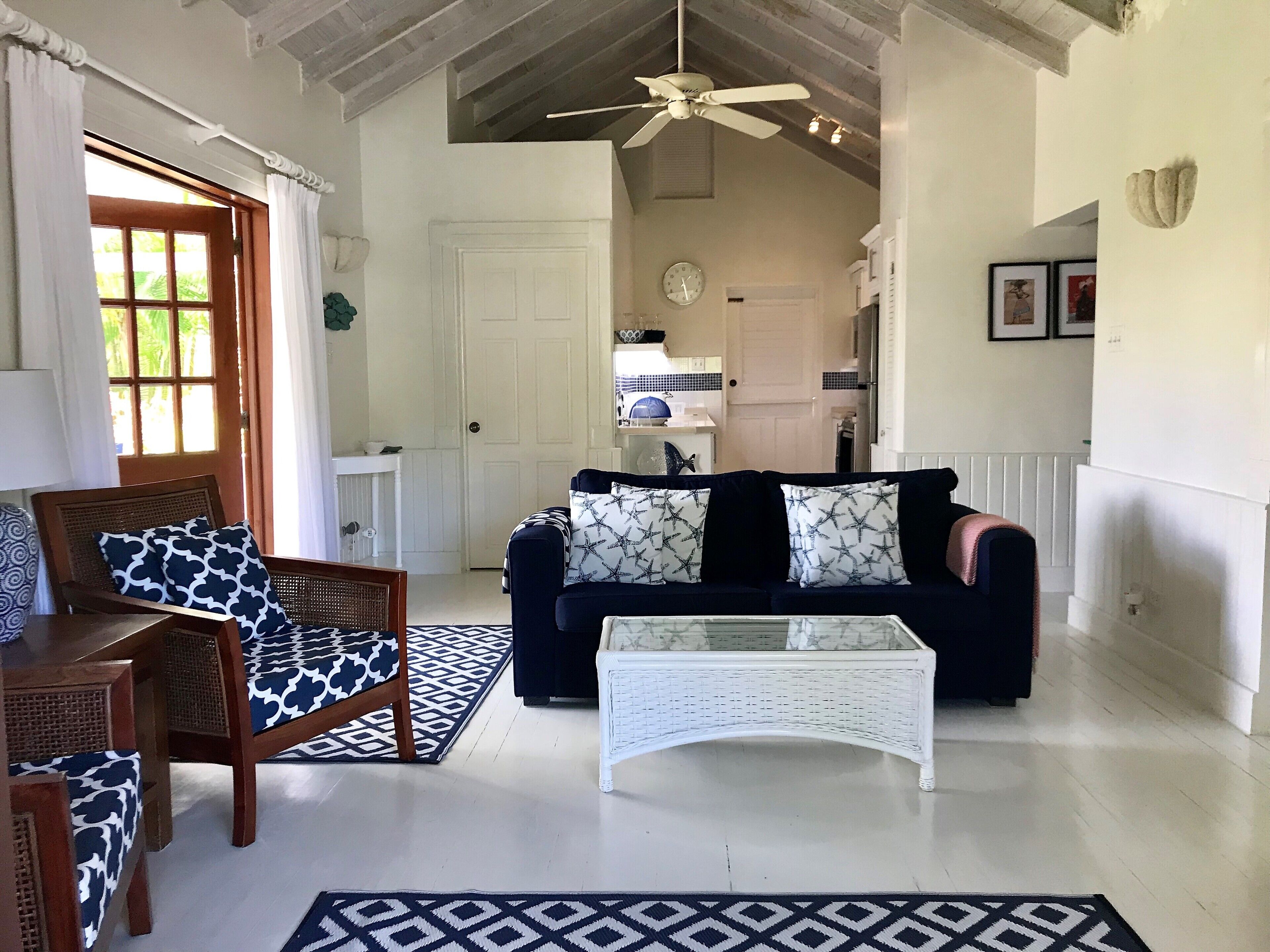 Una sala de estar con sofá, sillón, mesa de centro y alfombras estampadas.