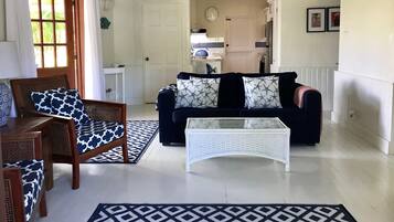 Una sala de estar con sofá, sillón, mesa de centro y alfombras estampadas.