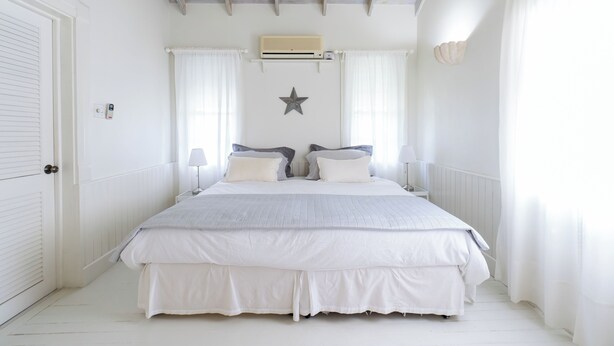 A bedroom with a large bed, white walls, a ceiling fan, and a star decoration.