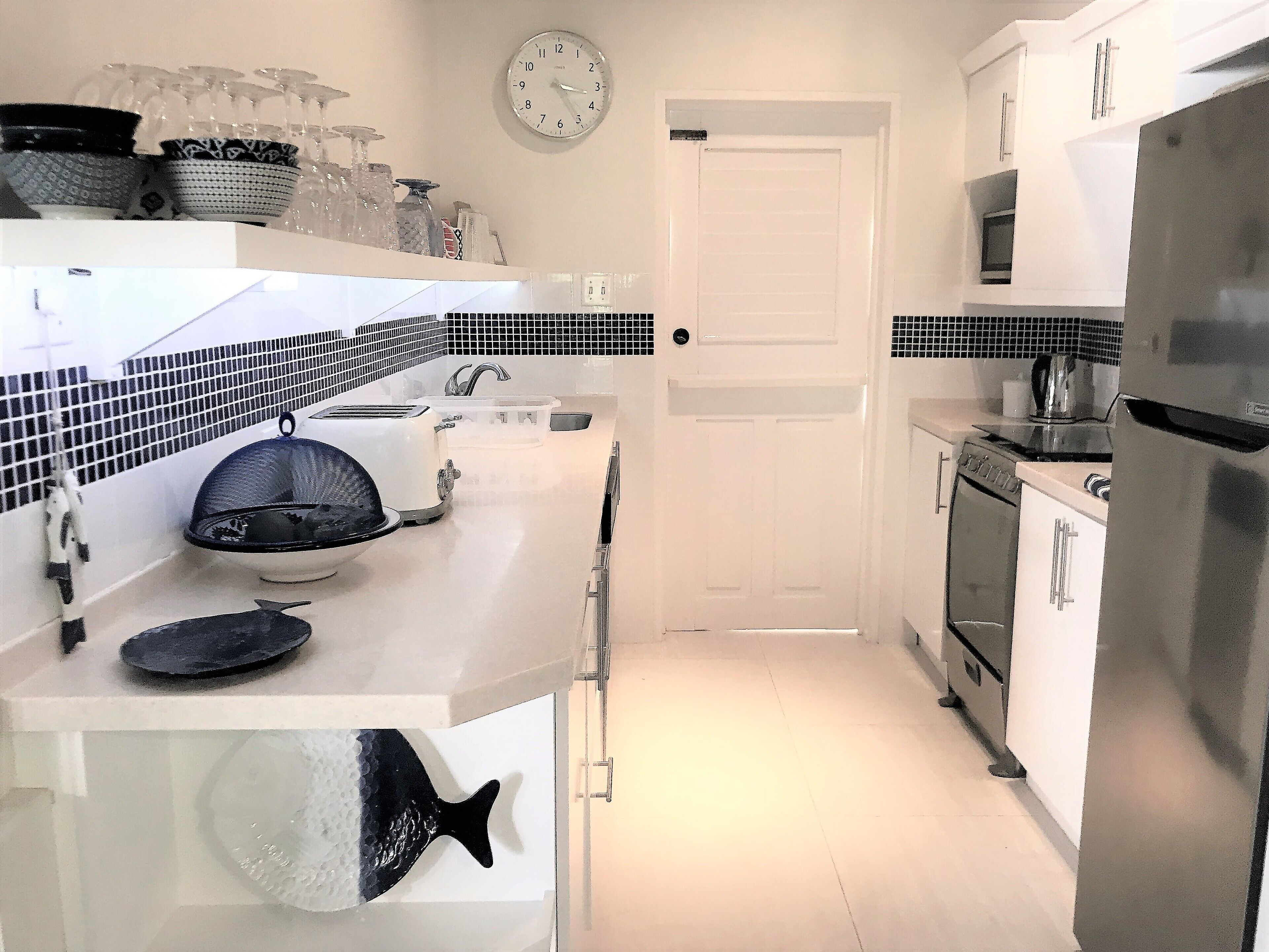 A modern kitchen with white cabinets, a stainless steel refrigerator, a microwave, and a toaster.