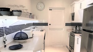 A modern kitchen with white cabinets, a stainless steel refrigerator, a microwave, and a toaster.