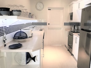 A modern kitchen with white cabinets, a stainless steel refrigerator, a microwave, and a toaster.