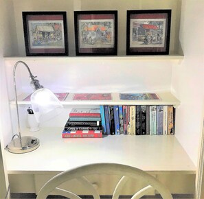 A bookshelf with books and three framed pictures on a wall.