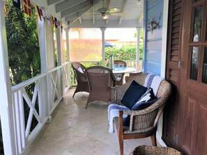 Eine überdachte Veranda mit Korbmöbeln und einer Holztür.