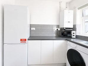 A modern kitchen with a white refrigerator, a built-in oven, a microwave, and a dishwasher.