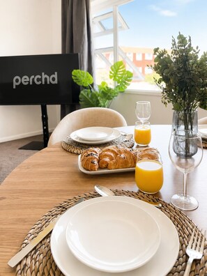 A breakfast setting with croissants, orange juice, and a glass of water on a table with a woven placemat.