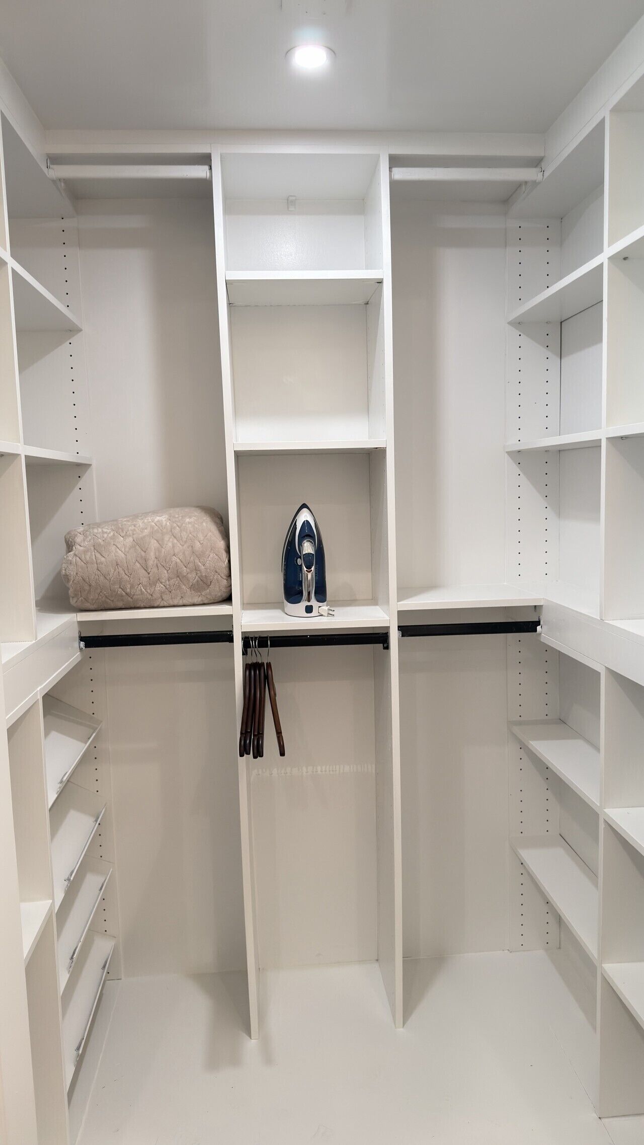 A walk-in closet with open shelving, a hanging rod, and a built-in ironing station.