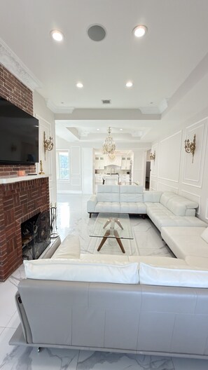 A modern living room with a sectional sofa, a flat-screen TV, and a fireplace. - Elegant 2-Bedroom Apartment with Stunning Manhattan Views and Free Parking (Weehawken Township)
