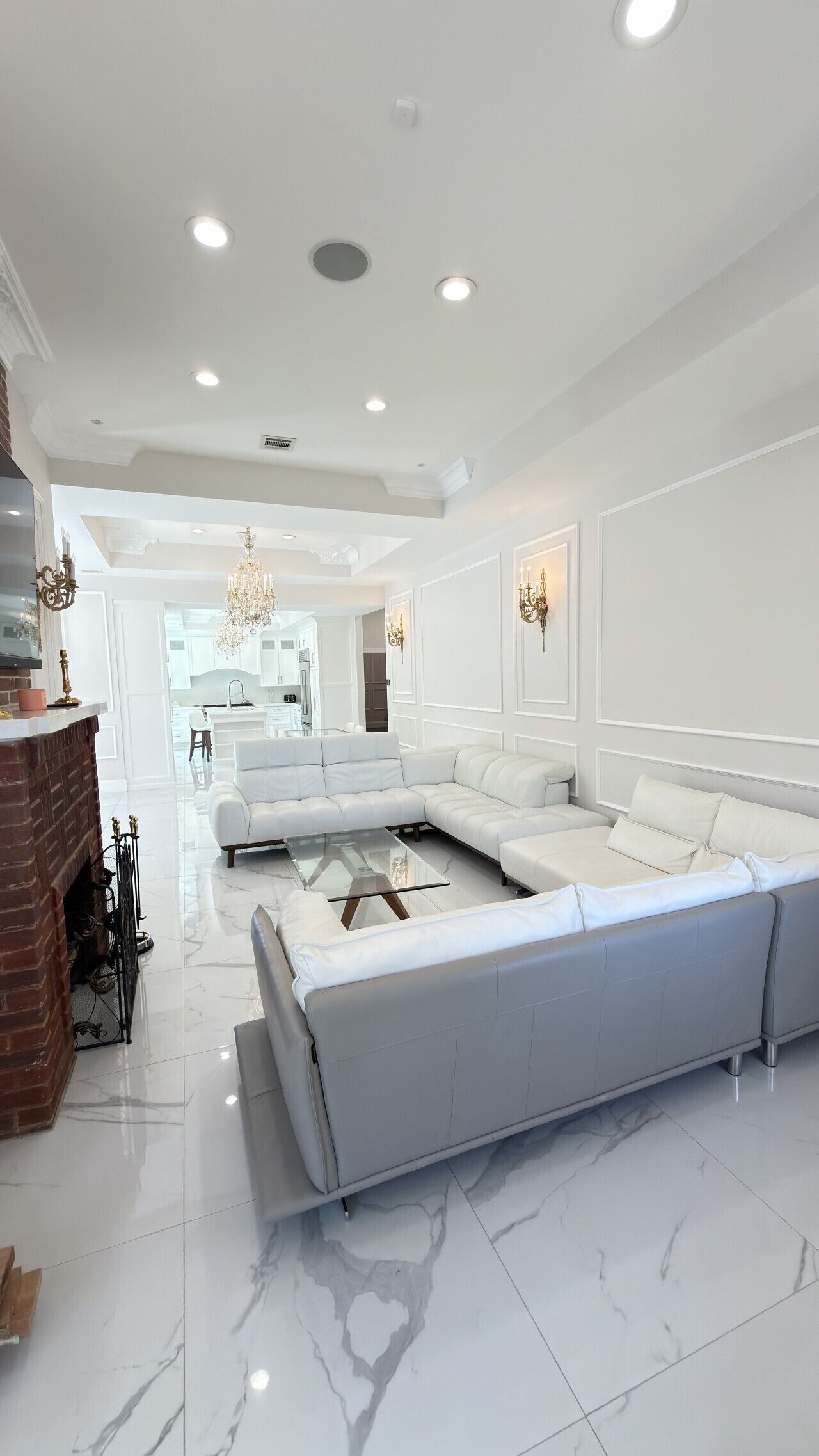 A modern living room with a sectional sofa, a glass coffee table, and a fireplace.