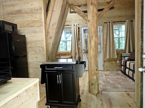 A cabin interior with a kitchen area, a dining table, and a bed. - Tiny Cabin with Fire Pit & Covered Porch Retreat in Salem, Missouri (Salem)