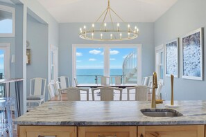 A kitchen with a marble countertop, a gold faucet, and a view of the ocean. - Oceanfront pool with theater and games (North Topsail Beach)