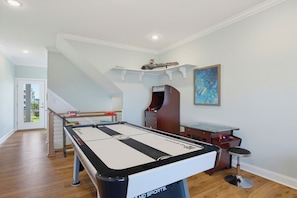 Ein Billardtisch in einem Raum mit Holzboden, einer Treppe und einem Gemälde an der Wand.