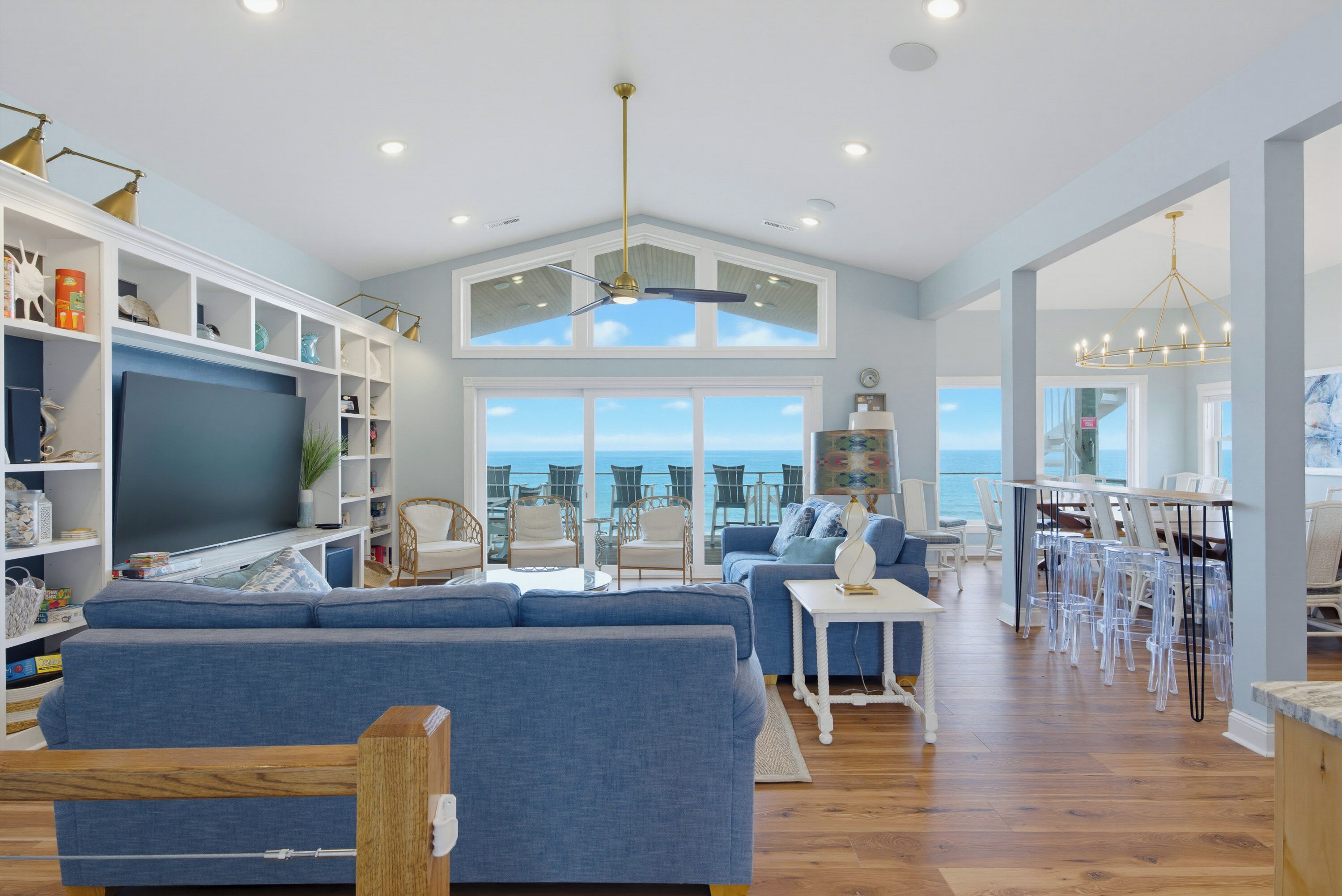 A spacious living room with a large sofa, a television, and a dining area with chairs and a table.