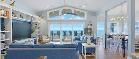 A spacious living room with a large sofa, a television, and a dining area with chairs and a table.