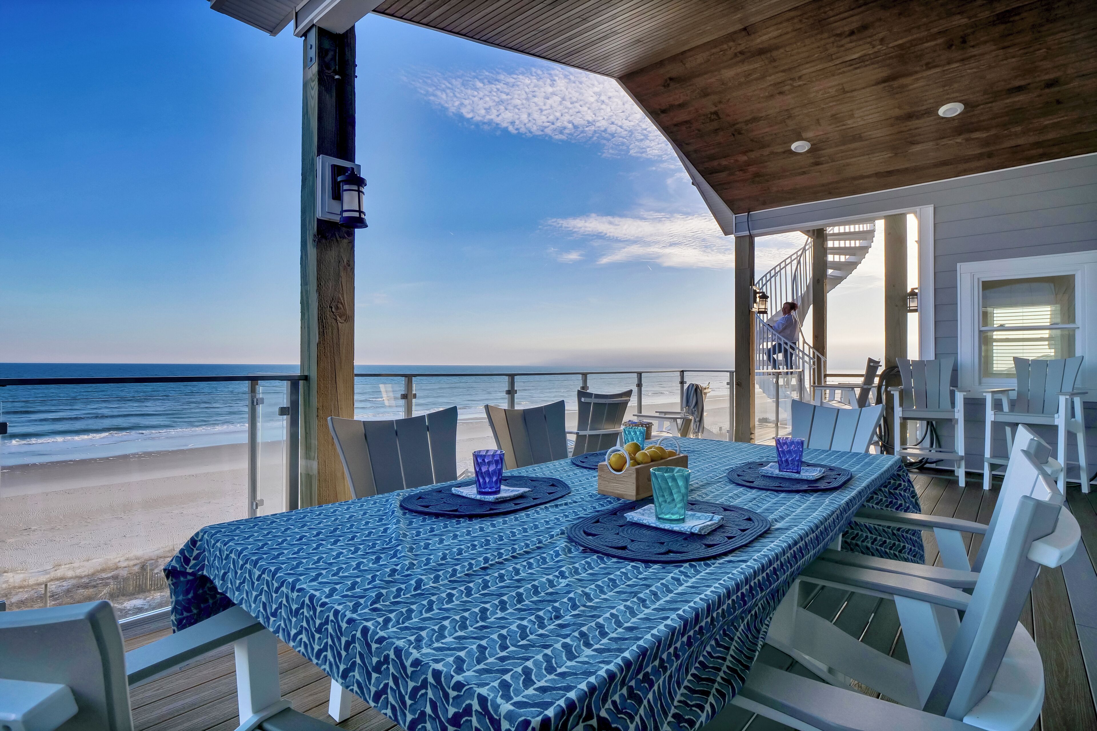 A covered outdoor dining area with a view of the beach and ocean.