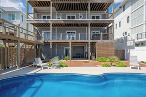 Ein mehrstöckiges Wohngebäude mit Schwimmbad, Außenbereich zum Sitzen und einer überdachten Terrasse.