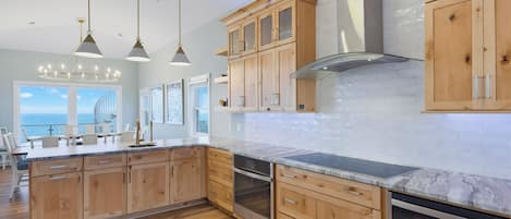 A modern kitchen with wooden cabinets, a stainless steel range hood, and a large island with a built-in oven.