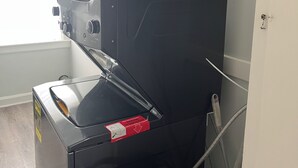 En kompakt, moderne apparat, sandsynligvis en vaskemaskine eller tørretumbler, med et kontrolpanel til venstre og en dør til højre.