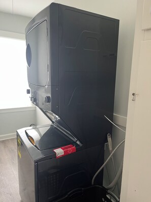 Ein kompaktes, modernes Gerät, vermutlich eine Waschmaschine oder ein Trockner, mit einer Bedieneinheit links und einer Tür rechts.
