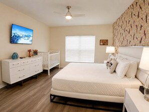 A bedroom with a bed, a dresser, a crib, a ceiling fan, and a TV on the wall. - 5BR Fantastic Villa  Pool & Game Room Near Disney (Kissimmee)