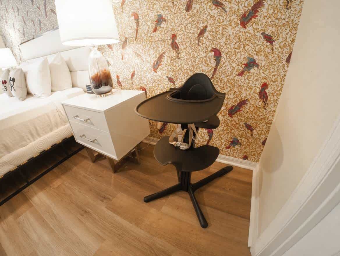 A bedroom with a bed, bedside table, lamp, and a chair with a unique design.