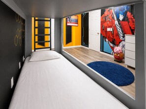 Ein modernes Schlafzimmer mit einem Bett, einem blauen Teppich, einer Tür und einer Wand mit geometrischem Muster.