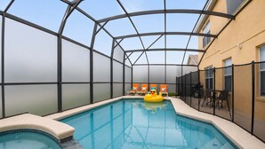 An indoor swimming pool with a glass ceiling, surrounded by lounge chairs and a table. - 5BR Fantastic Villa  Pool & Game Room Near Disney (Kissimmee)