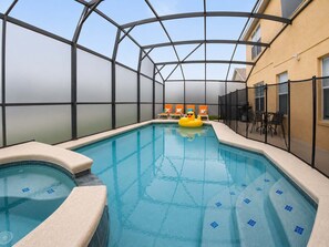 Ein Hallenbad mit Glasdach, umgeben von Liegestühlen und einem Tisch.