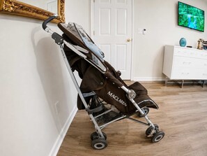 A room with a white dresser, a television mounted on the wall, and a stroller leaning against the wall. - 5BR Fantastic Villa  Pool & Game Room Near Disney (Kissimmee)