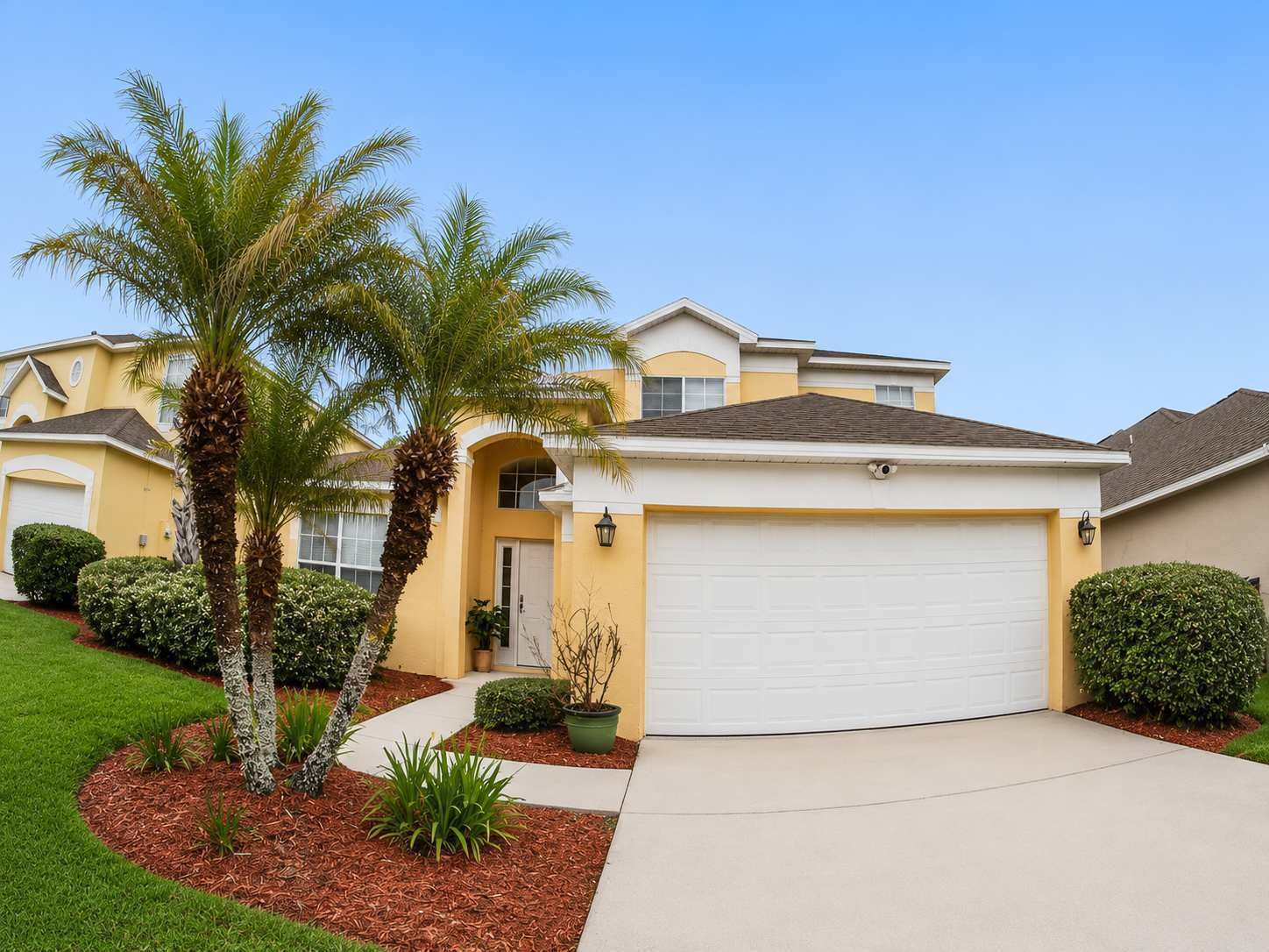 A residential house with a garage, a driveway, and a well-maintained lawn.