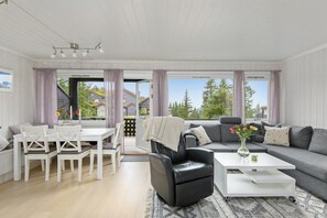 A modern living room with a sofa, a dining table with chairs, and a coffee table. - Modern apartment in Hafjell (Gudbrandsdalen)