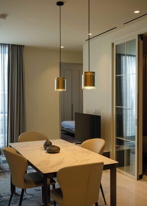 Ein Hotelzimmer mit Esstisch, Stühlen, einem Bett, einem Fernseher und einer Schiebeglastür.