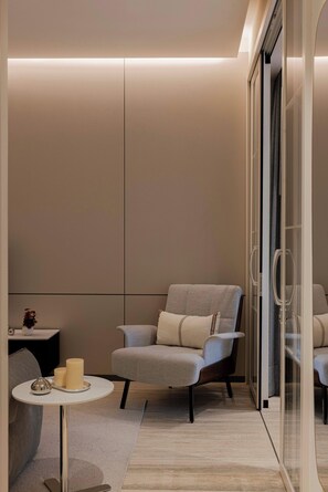 A modern interior with a grey armchair, a small round table with candles, and a glass partition. - Quiet Courtyard 2BR Suite with AC (Ciudad de México)