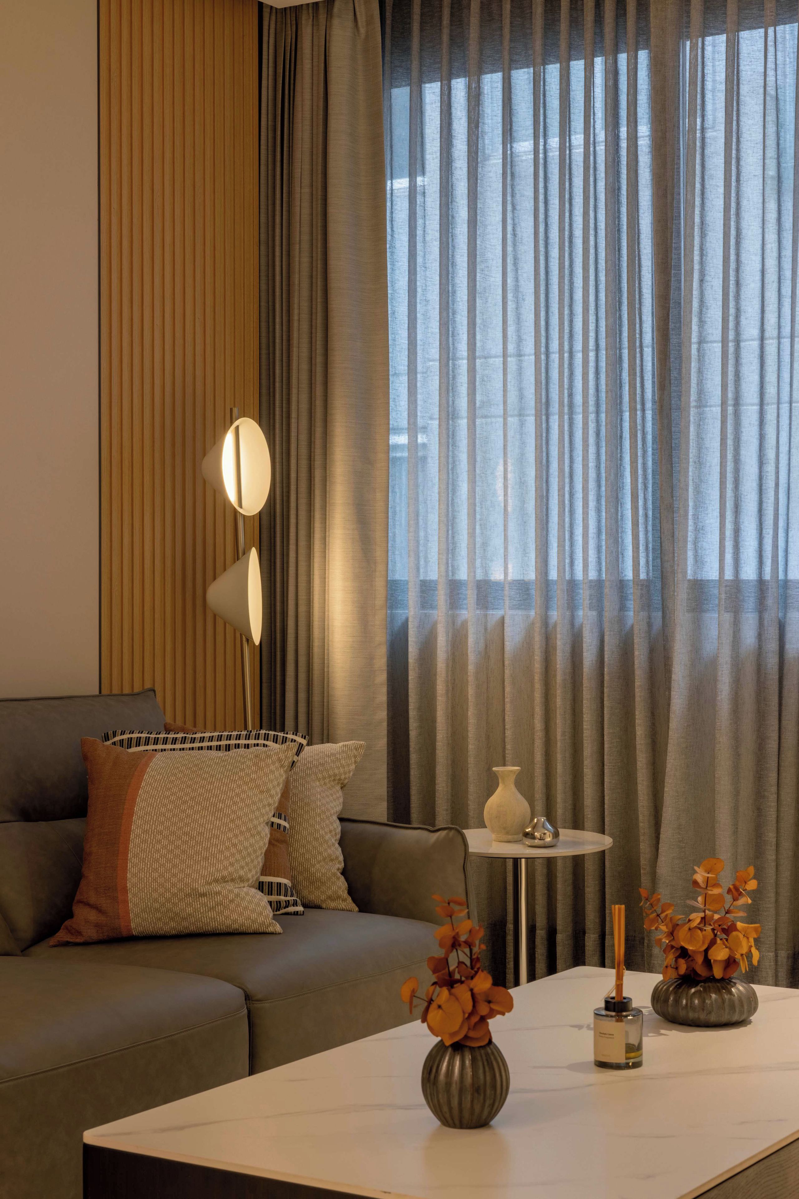 Ein modernes Wohnzimmer mit einem grauen Sofa, einem runden Couchtisch und einem Beistelltisch mit Dekoration.