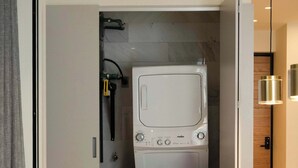 A compact kitchen with a built-in washer and dryer, a dining area with a marble table, and a modern pendant light. - Quiet Courtyard 2BR Suite with AC (Ciudad de México)