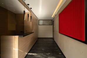 A narrow hallway with a reception desk, wooden paneling, a black floor, and a red acoustic panel on the right wall. - Family 2BR Apartment with Street-View Balcony in Polanco (Ciudad de México)