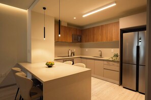A modern kitchen with a central island, wooden cabinets, a stainless steel refrigerator, and a microwave. - Family 2BR Apartment with Street-View Balcony in Polanco (Ciudad de México)