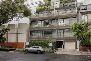 Un edificio moderno de varios pisos con un automóvil estacionado enfrente.