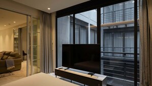 A modern hotel room with a large bed, a flat-screen TV, a sofa, and a sliding glass door leading to a balcony with a city view. - Grand 3BR Apartment with Interior Balcony in Polanco (Ciudad de México)