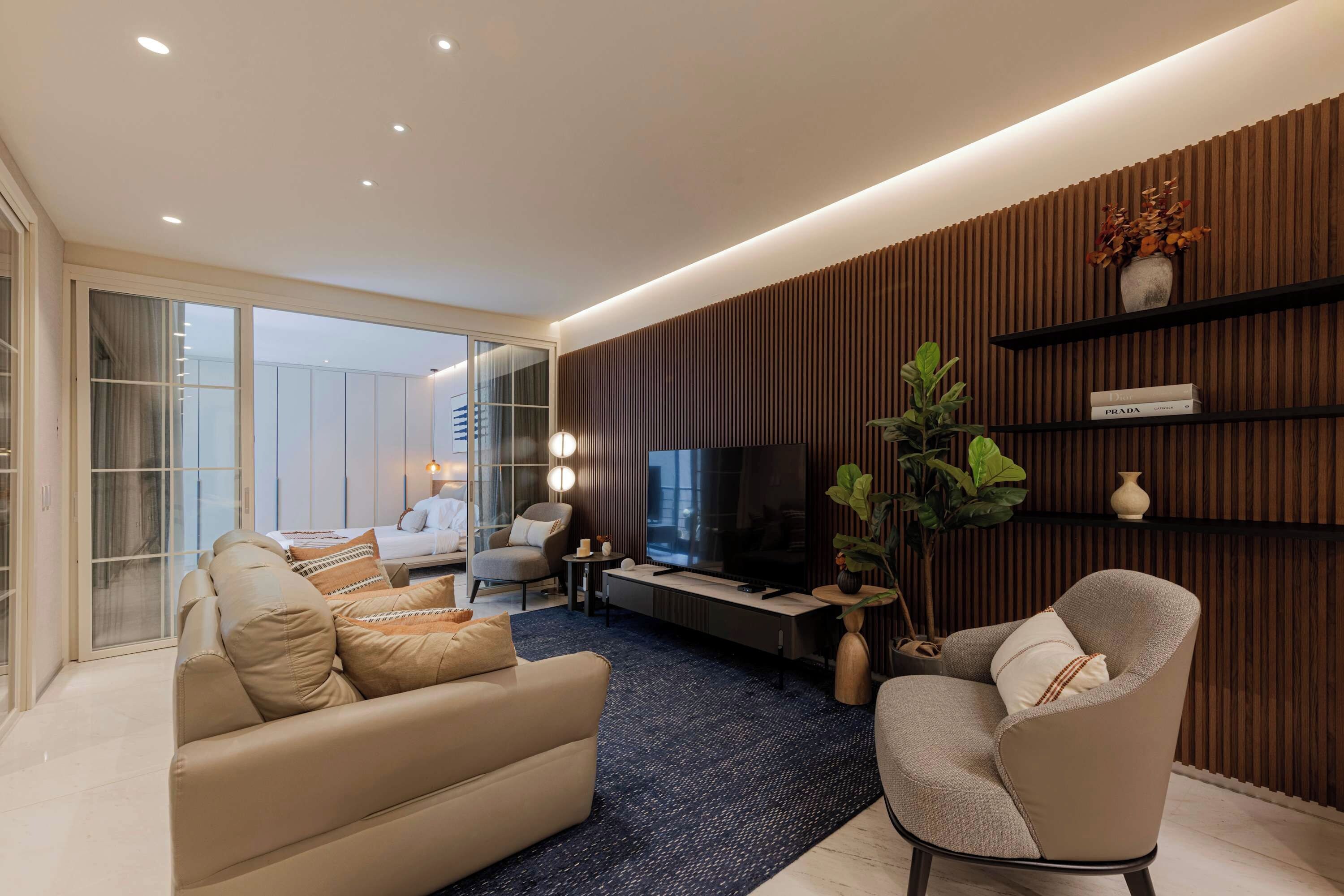 Ein modernes Wohnzimmer mit einer Couch, einem Sessel, einem Fernseher und einem Bücherregal.