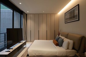 Quarto moderno com cama, escrivaninha e televisão.